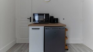 Une petite cuisine équipée d’un four à micro-ondes, d’une machine à café et d’un réfrigérateur, le tout installé sur un plan de travail en bois.