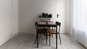 Un comedor con una mesa y cuatro sillas, una cafetera y un estante con objetos.