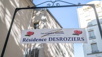 Letrero que dice 'Résidence DESROZIERS', con un mensaje de bienvenida e ilustración de una rosa.