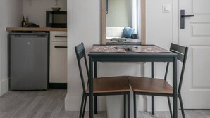A compact kitchen with a refrigerator, microwave, and coffee maker on a white shelf.
