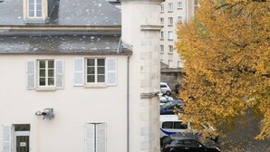 A building with a tower, a car parked in front, and a tree with yellow leaves.