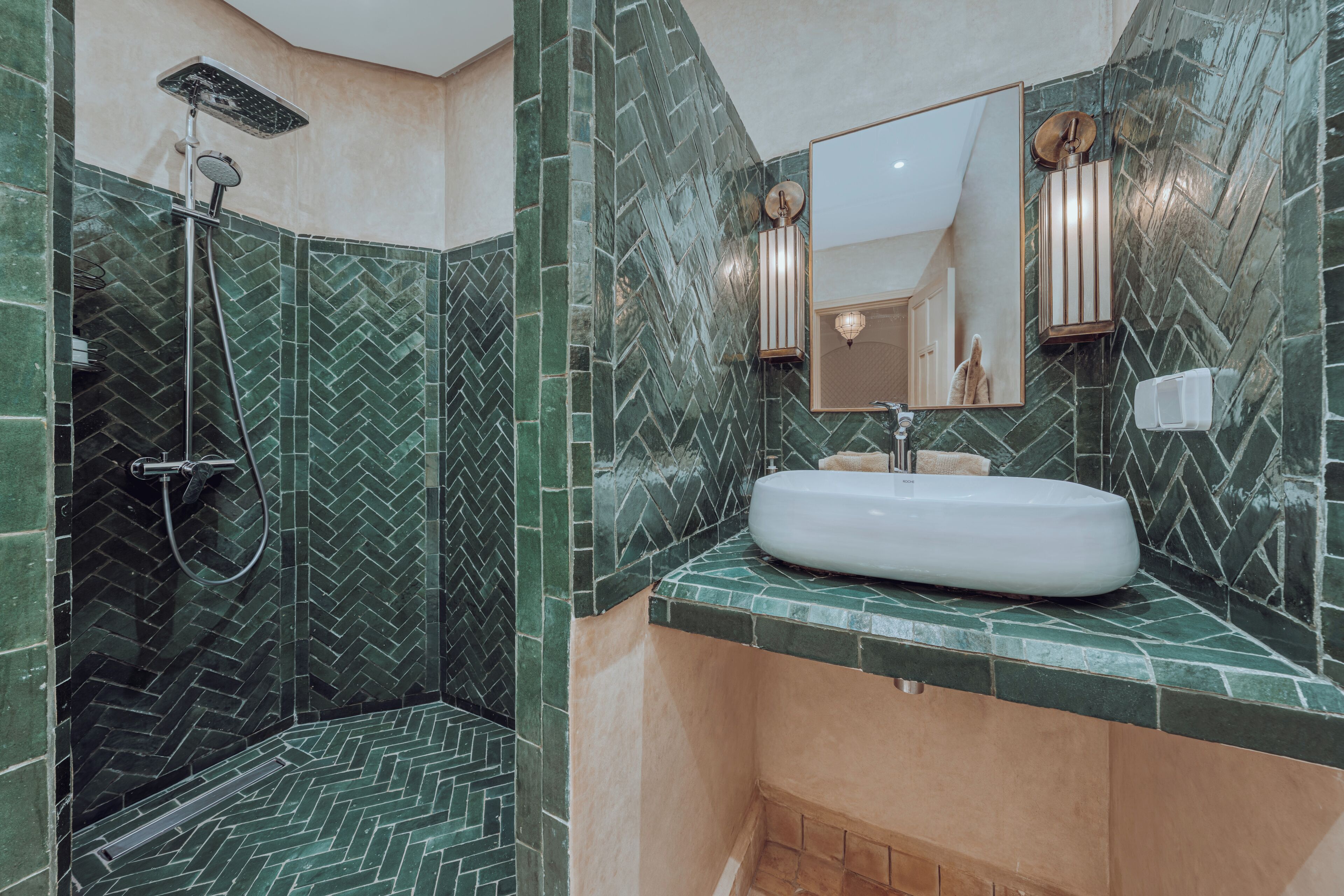 Un baño con ziguezag de baldosas, un lavabo blanco y una ducha con cabezal de ducha manual.