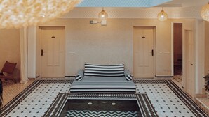 A hotel room with a bed, two doors, a patterned floor, and hanging lights.