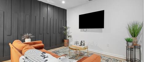 Una sala de estar moderna con un sofá, una mesa de centro y un televisor de pantalla plana montado en la pared.