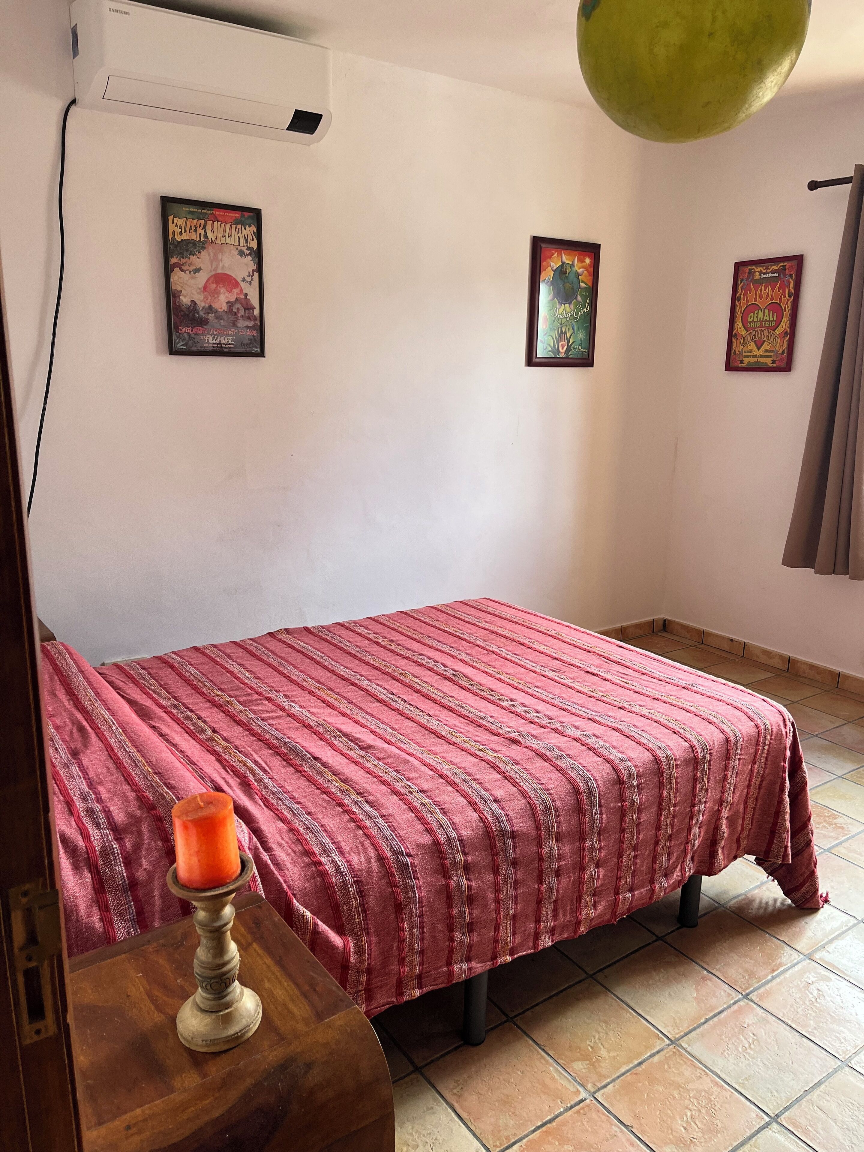 Un dormitorio con una cama, aire acondicionado de pared y una lámpara en el techo.