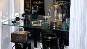 A coffee shop with a neon sign, glass shelves with coffee-making equipment, and a coffee grinder.