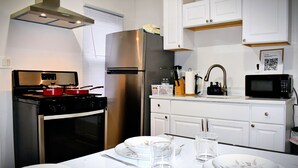 A modern kitchen with stainless steel appliances, white cabinetry, and a dining area set for four.