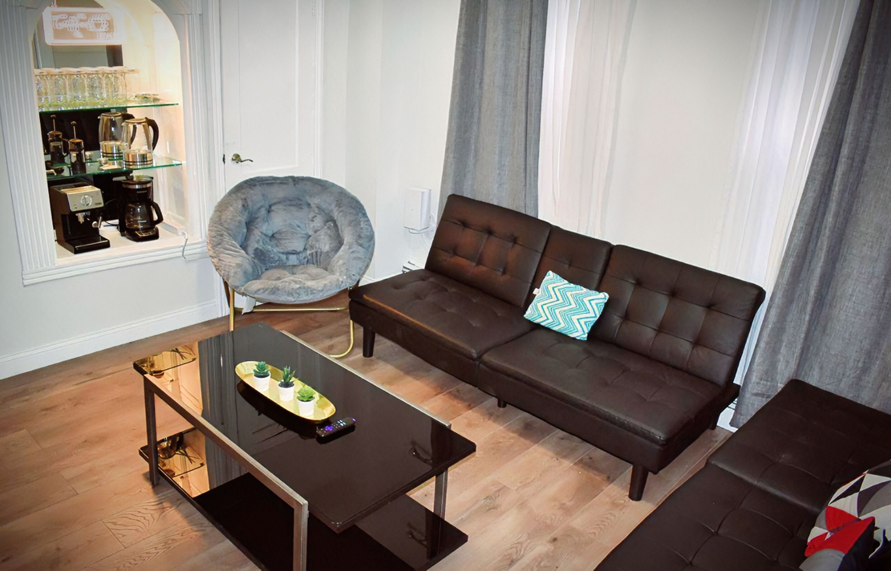 A living room with a dark brown sofa, a glass coffee table, and a chair.
