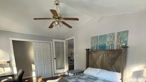 Un dormitorio con cama de madera, ventilador de techo y vista a un pasillo.