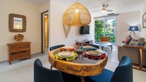 Un comedor con una mesa redonda de madera, sillas azules y una lámpara colgante de fibras.