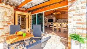 A rustic kitchen with a stone oven, wooden furniture, and a dining area with a table and chairs. - Villa Azimut - Cozy Home In Medulin With Sauna (Medulin)