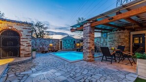 A stone patio with a swimming pool, outdoor seating, and a brick building with a covered area. - Villa Azimut - Cozy Home In Medulin With Sauna (Medulin)