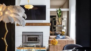 Un salon moderne avec une table ronde, deux chaises, un lampadaire et une cheminée.