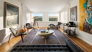 Un salon moderne doté d’une grande fenêtre, d’un télescope et d’une table basse.