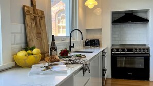 Une cuisine moderne dotée d’un grand îlot central, d’une cuisinière à gaz et de luminaires suspendus.