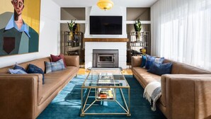 Un salon moderne avec une cheminée, des canapés en cuir, une table basse et un grand tableau accroché au mur.