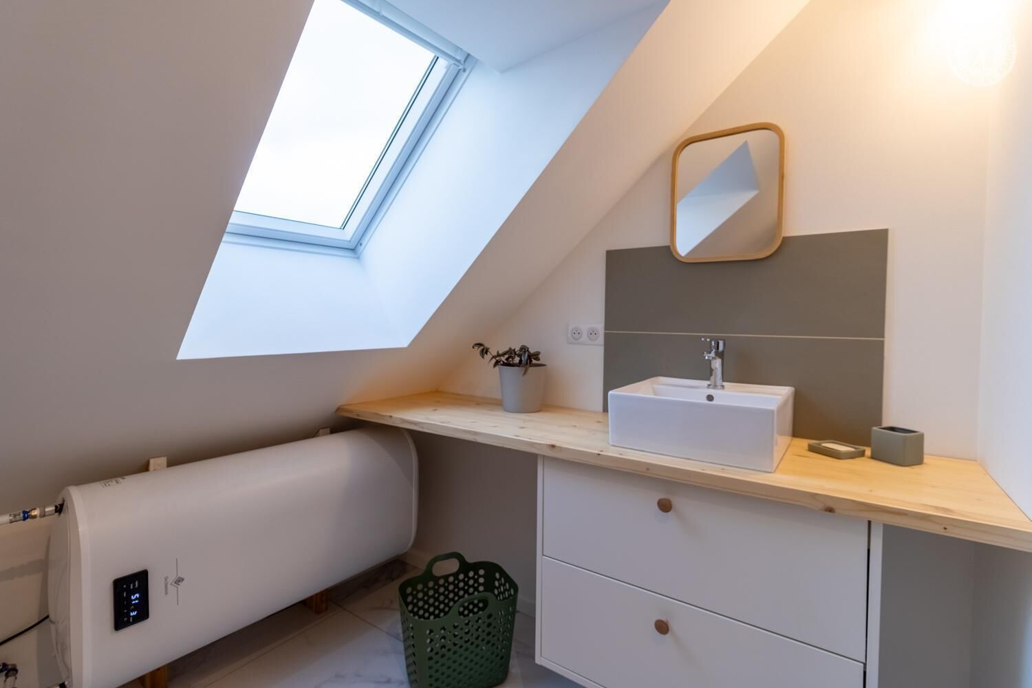 A modern bathroom with a skylight, a sink, a mirror, and a radiator.
