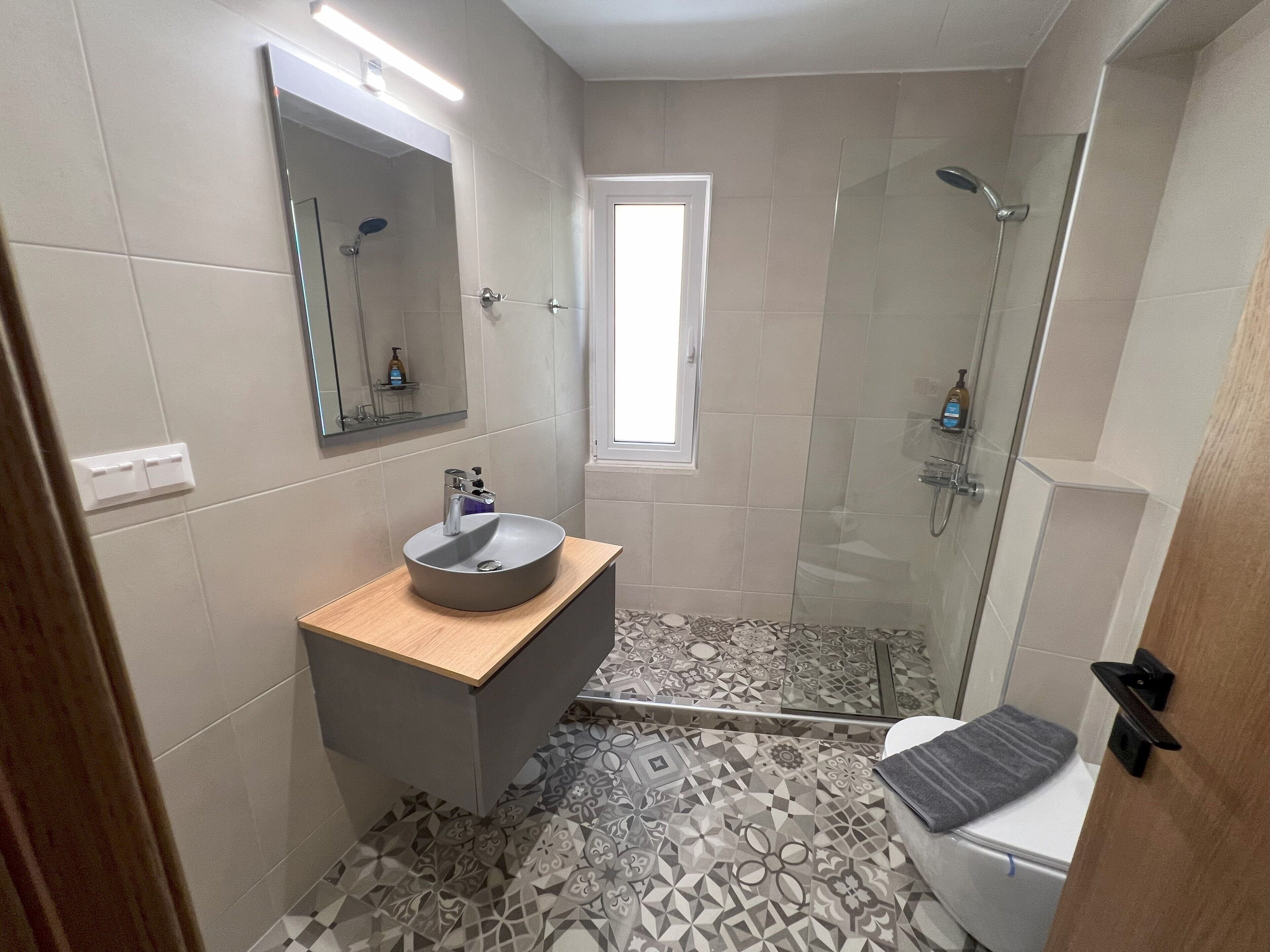Un baño con lavamanos, espejo, ducha e inodoro.