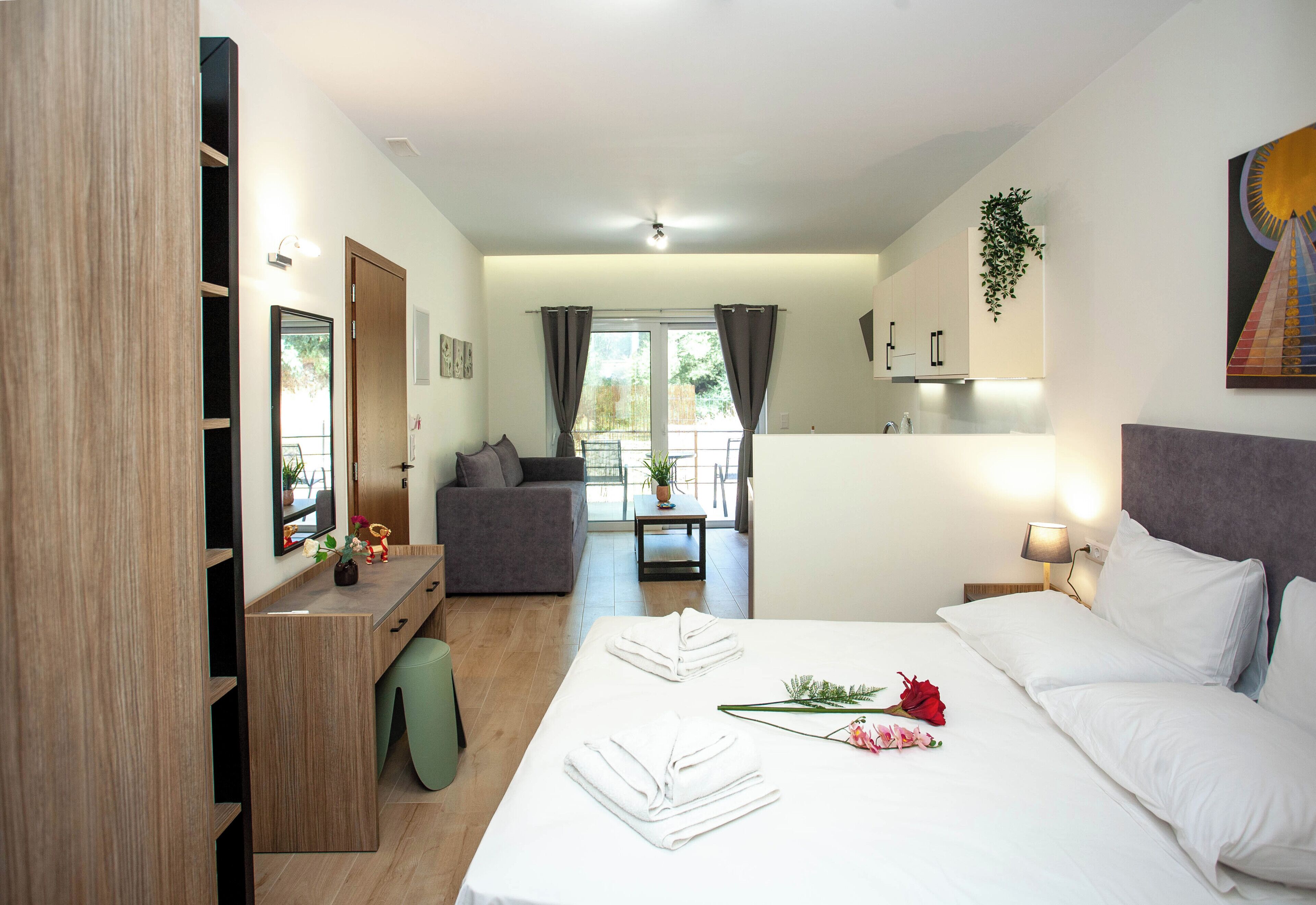 Habitación de hotel con cama, escritorio, sofá, mesa de comedor y vistas al exterior.