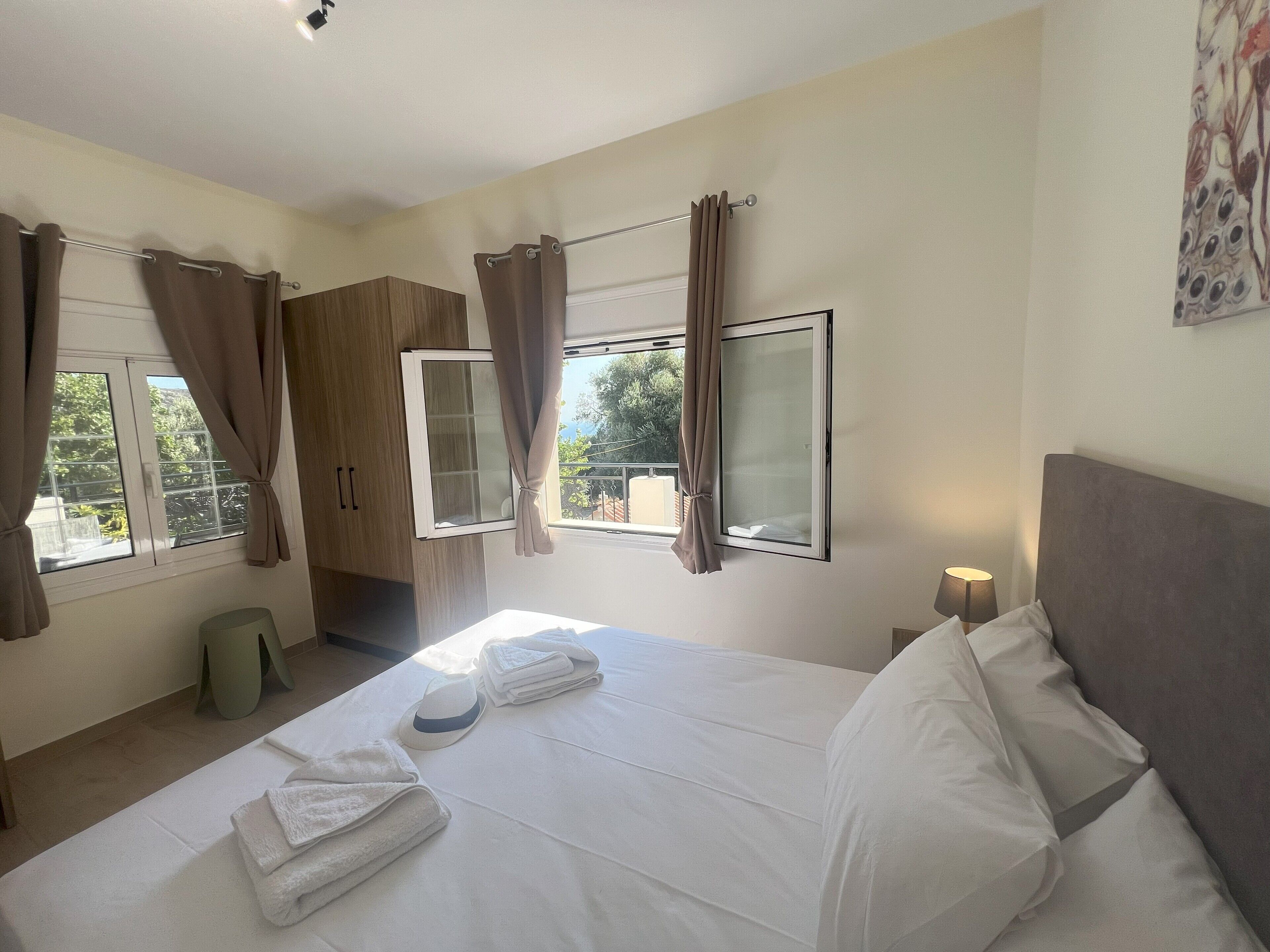 A bedroom with a bed, curtains, a window, and a nightstand.