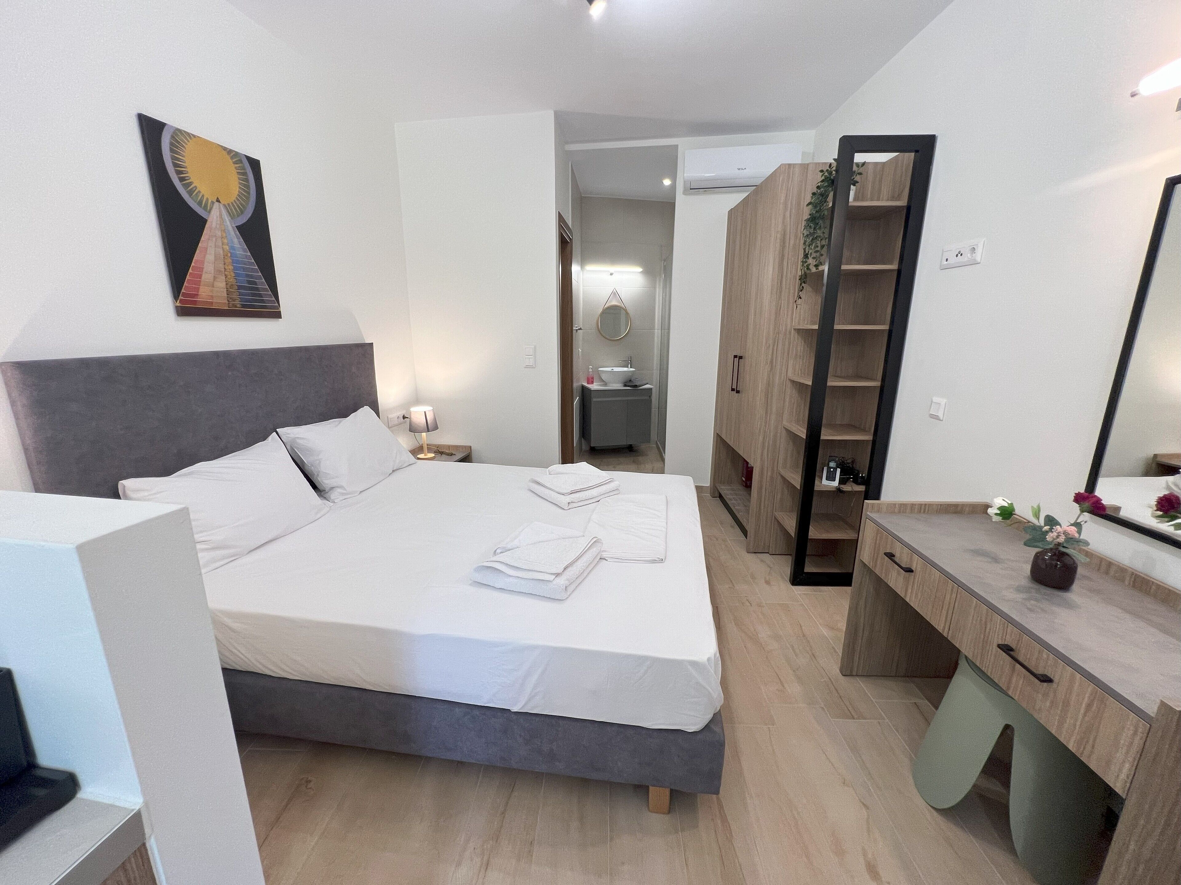 Una camera d'albergo moderna con un letto grande, comodini, una scrivania e un armadio.