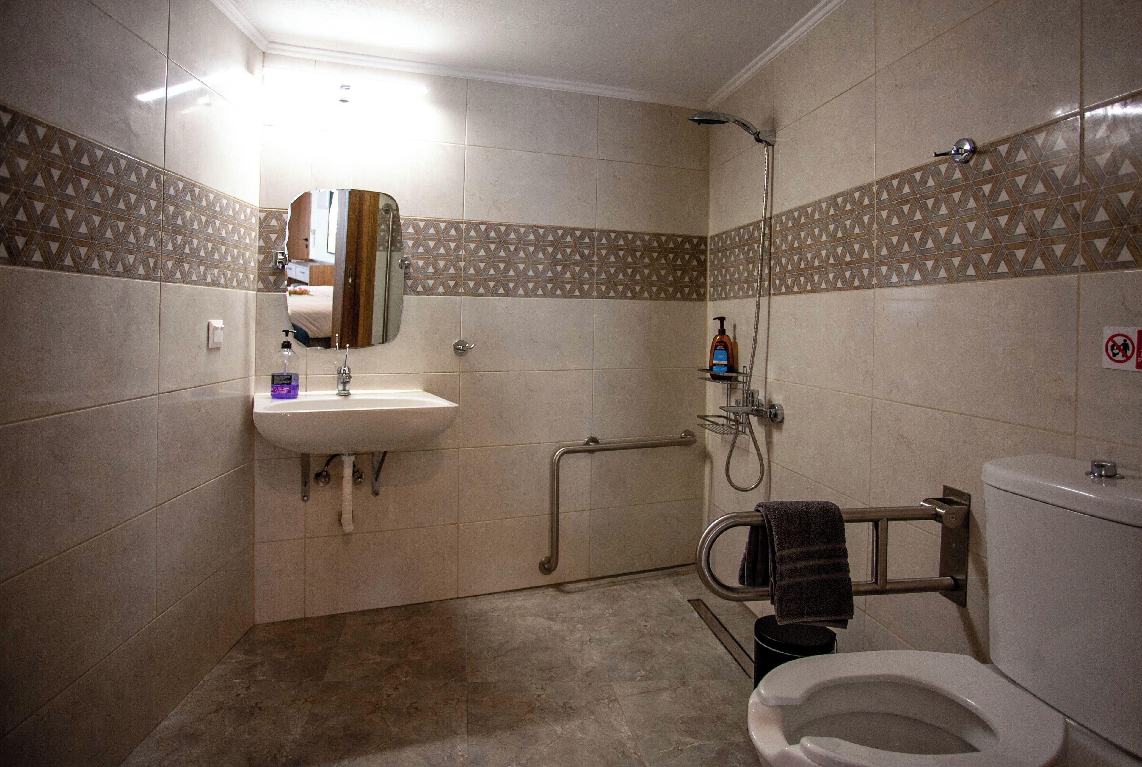 A bathroom with a sink, mirror, toilet, and shower.