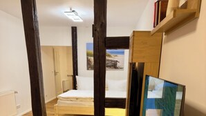 A room with a bed, wooden floor, and a television. - Historic living near the town hall and Steintor (Malchin)