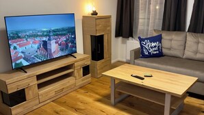 A modern living room with a wooden entertainment unit, a flat-screen TV, a sofa, and a coffee table. - Historic living near the town hall and Steintor (Malchin)