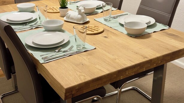 A dining table set with plates, bowls, cutlery, and a small potted plant. - Historic living near the town hall and Steintor (Malchin)