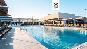 A swimming pool with lounge chairs and umbrellas, a modern building with a flat roof, and a clear sky. - Stay Near Disney Magic | Gorgeous 4BR Villa w BBQ (Kissimmee)