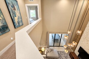 Ein Innenraum mit hohen Decken, einer Treppe, einem Essbereich mit Blick und modernen Leuchten.