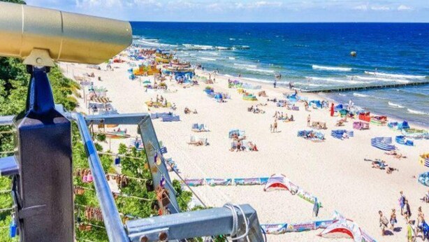 Una spiaggia con vista libera sull'oceano, ombrelloni e bagnanti.