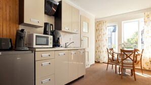 Una cucina moderna con frigorifero, microonde, macchina del caffè e tostapane. È presente una zona pranzo con tavolo e sedie.