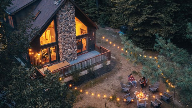 A cabin with a stone exterior, a wooden deck, and a fire pit area.