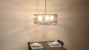Een eettafel met vier stoelen, een hanglamp en een stopcontact.