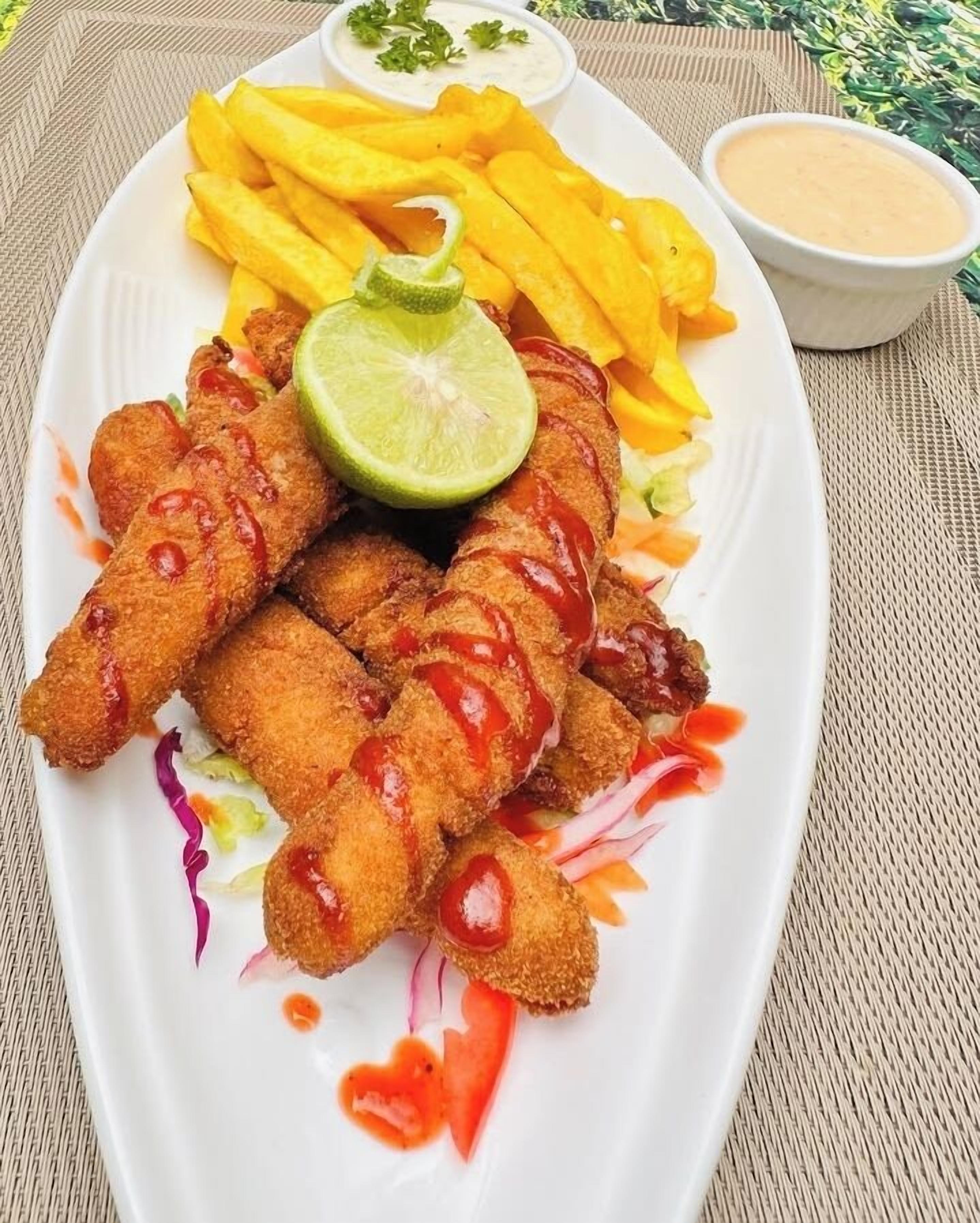 A plate of breaded and fried food items, possibly chicken tenders, accompanied by French fries and a lime wedge.