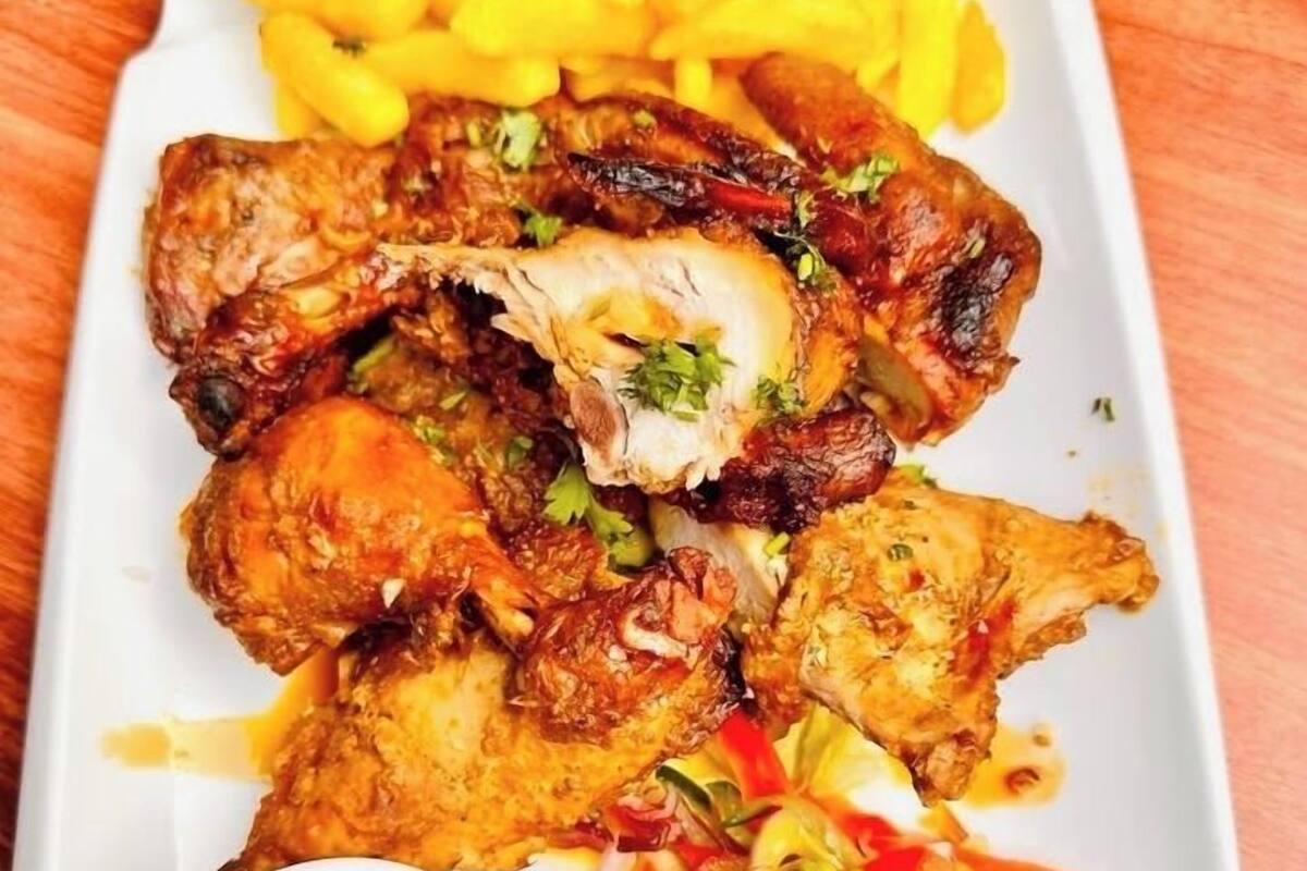 A plate of grilled chicken wings, French fries, and a side salad with two dipping sauces.