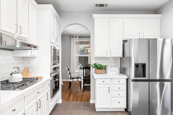 A modern kitchen with white cabinetry, stainless steel appliances, and a central island with a bread container.
