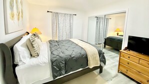 Un dormitorio con cama, cómoda, televisor y espejo.