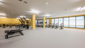 Et fitnesscenter med træningsudstyr, store vinduer og en lys, rummelig indretning.
