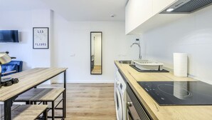 Et moderne køkken med træbordplade, indbygget ovn, vask og spejl.