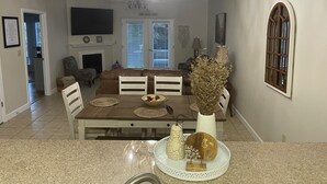 Uma sala de jantar com lustre, lareira e vista para a sala de estar.