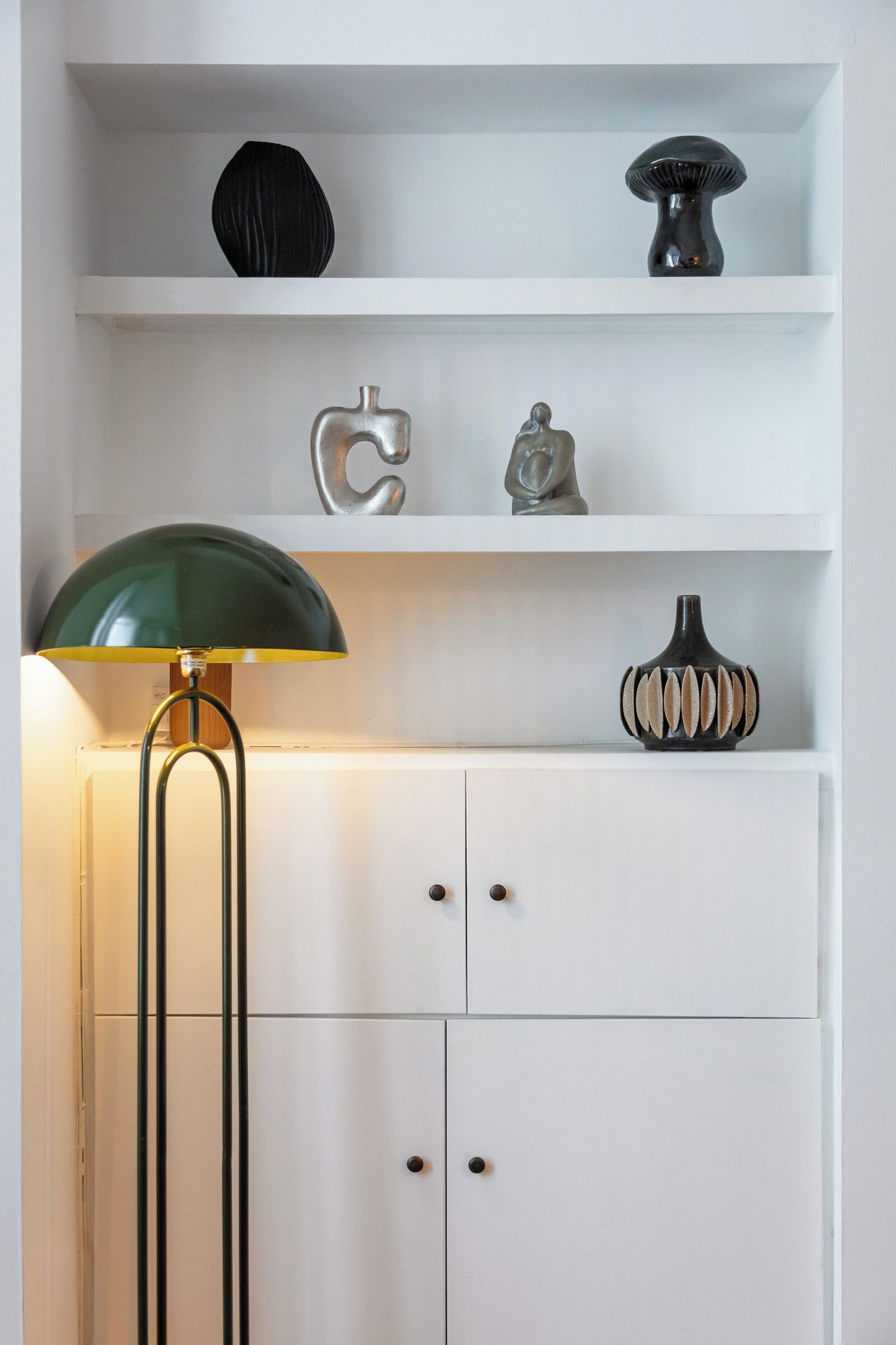 Un mueble blanco con tres cajones y una lámpara de pie verde con pantalla amarilla.