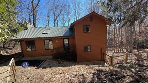 A two-story wooden cabin with a metal roof, surrounded by a wooded area. - Serene Mountain Retreat on Wolf Laurel Golf Course – Views of Hatley Pointe Ski (Mars Hill)