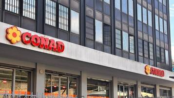 Un negozio CONAD con una facciata moderna, ampie vetrate e un ingresso ben visibile.