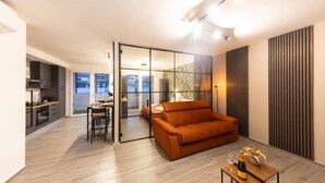 A modern living room with a sofa, a dining area, and a kitchen. - Urban Chic 2 Luxury Suite Apartments (Roma)