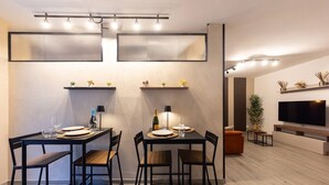 A modern dining area with two tables, chairs, and a flat-screen TV mounted on the wall. - Urban Chic 2 Luxury Suite Apartments (Roma)
