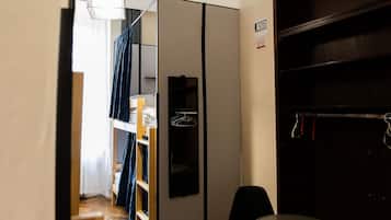 Una habitación funcional con kitchenette, una mesa de comedor y sillas, y un armario.