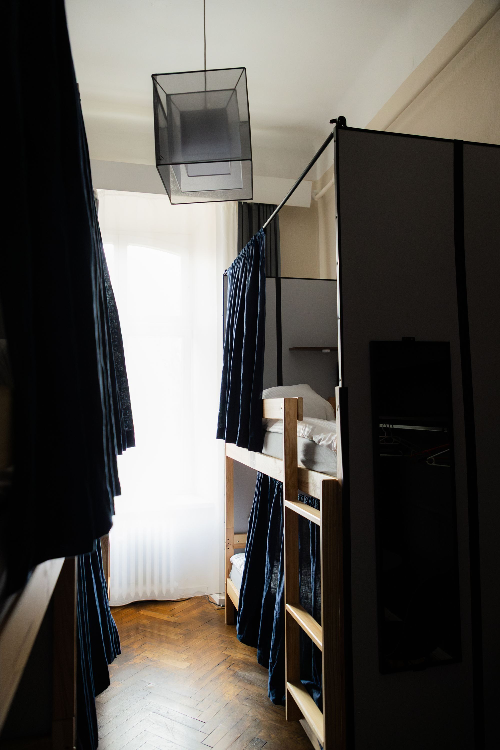 Habitación pequeña con una litera, una lámpara colgante y una ventana con cortinas.