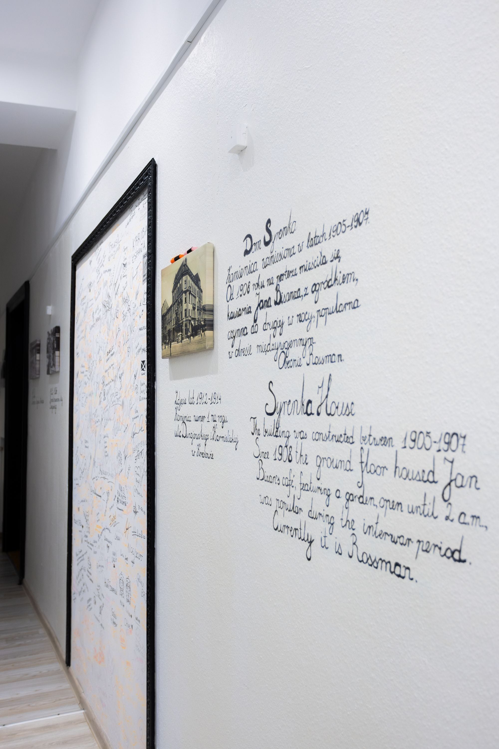 Un pasillo con una pizarra que muestra texto y una fotografía de un edificio.